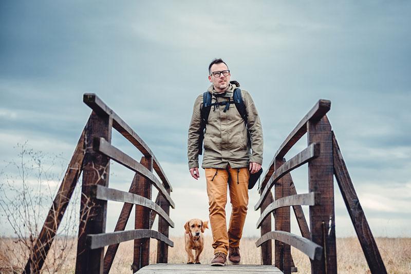 Hiker and dog crossing bridge
