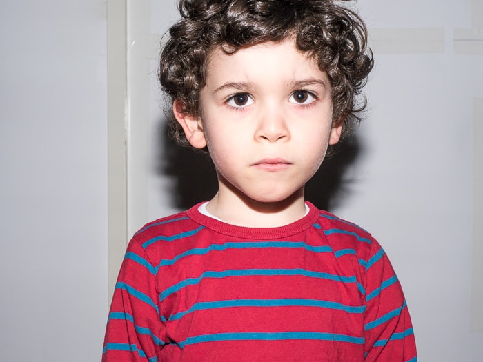 Portrait of young boy lit with hard light from direct flash