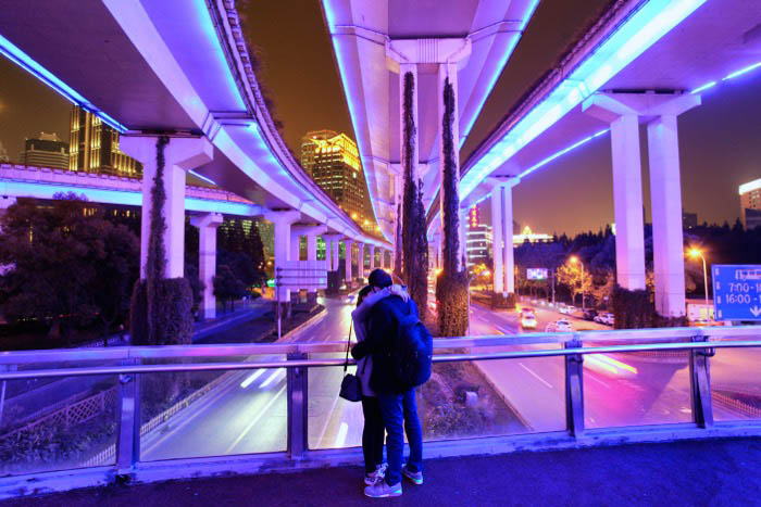 Night photography of a couple embracing under a modern bridge