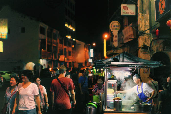 A night street photo of food stalls and passers by