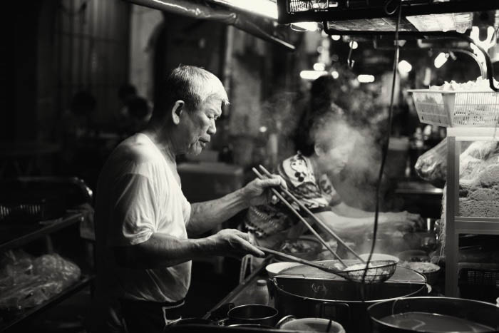 Night street shot of a man cooking in a food stall