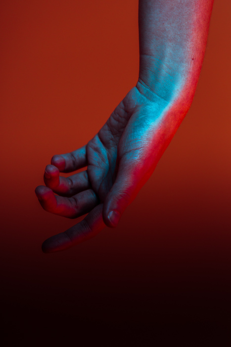 A blue and red toned hand against a red background - contrasting color photography
