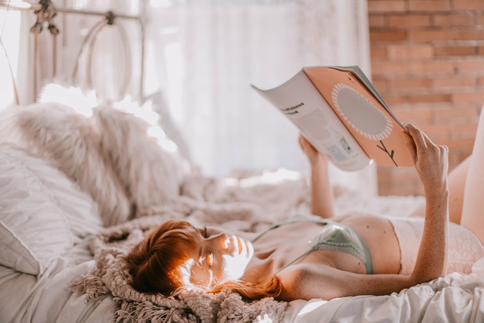 Woman laying on a bed and reading a book 