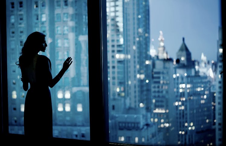 woman-looking-out-windows-urban-city-view-skyscrapers-evening-night-blue-black-white_troy-house-photography